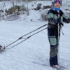 Mads og Oline på skitur i snøvær. Mads står foran og drar SnoComforten/pulken med Oline sittende i