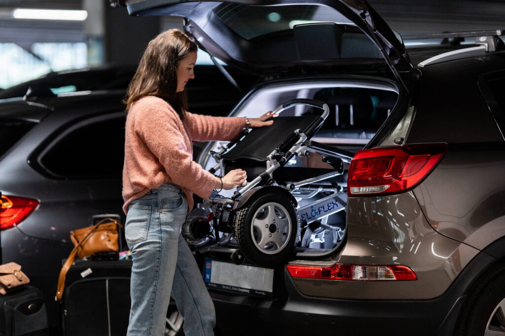 En kvinna har precis fällt ihop sin Eloflex elrullstol och lagt den i bagageutrymmet på bilen
