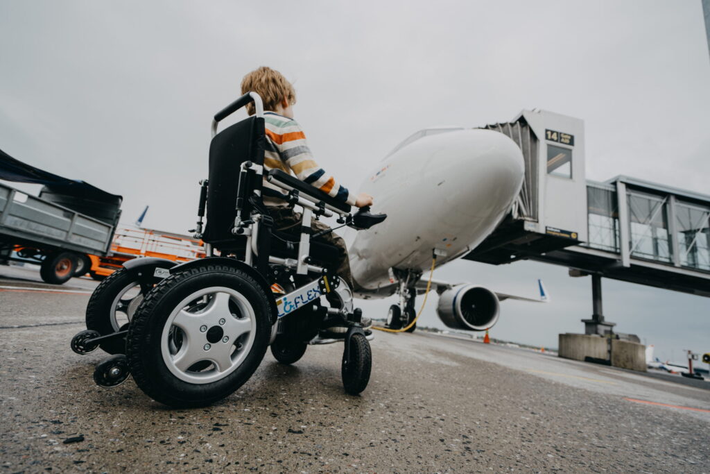 Barn i rullstol beundrar flyget framför sig.