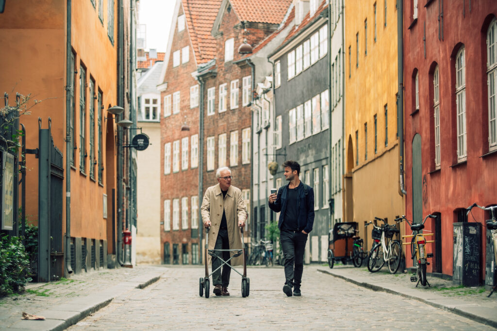 Mann med rollator på promenad i staden