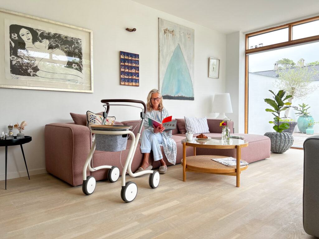 Dame sitter i sofa med Scandinavian Butler ved siden av