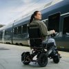 Kvinna i en Elio elektrisk rullstol på en tågperrong, med ett tåg i bakgrunden